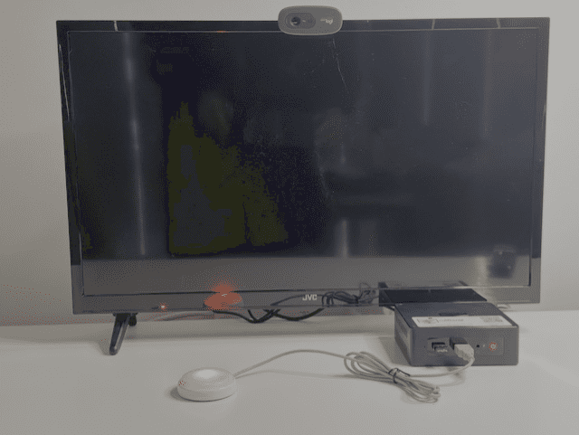 CallGenie device attached to television with the Do Not Disturb button activated.  The button has ared light on the television screen is black turned off.